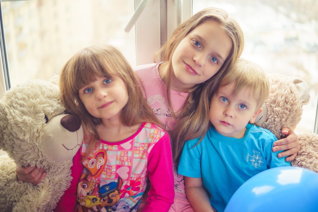 group portrait of three smiling children with toys